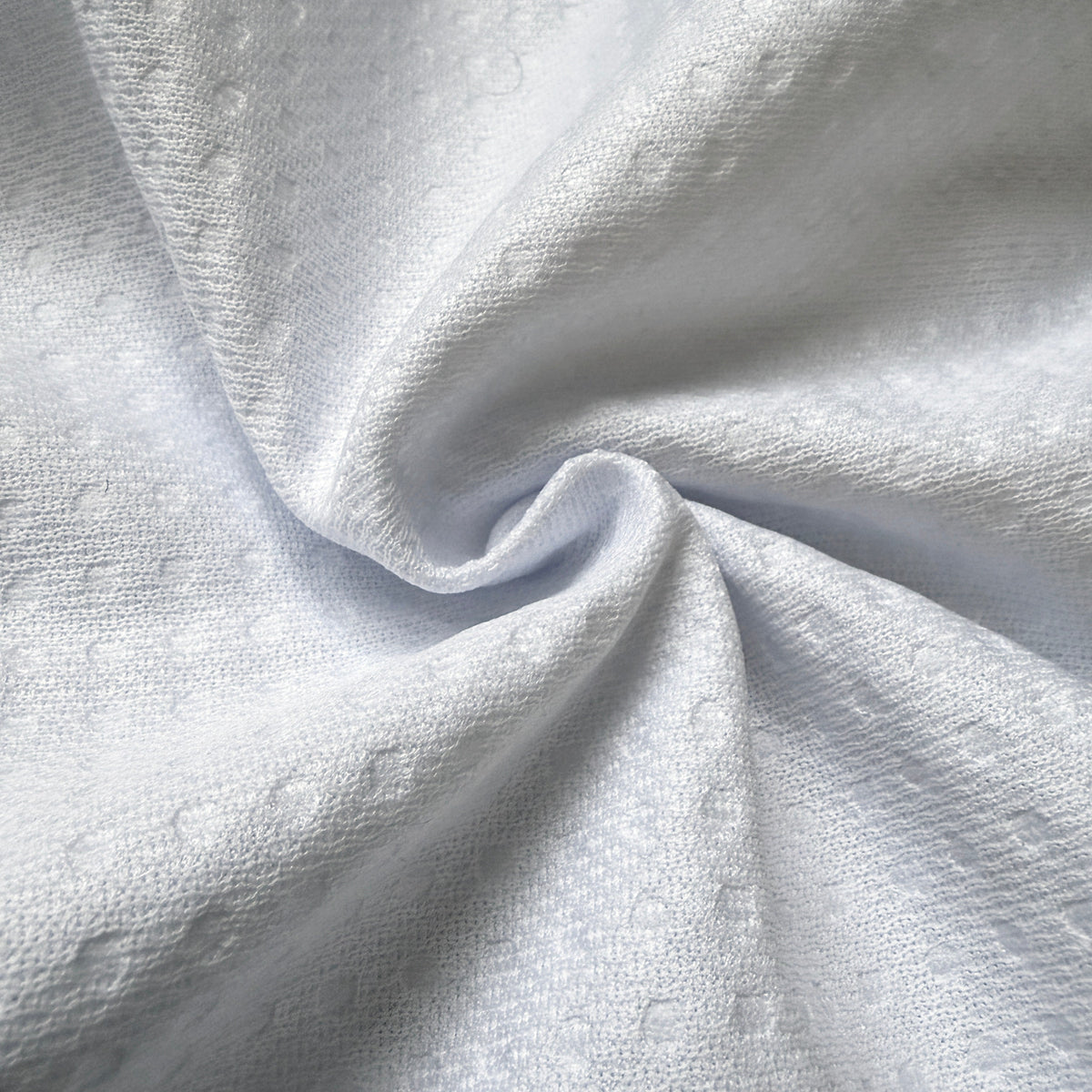 A close-up of light gray textured fabric with a subtle woven pattern, shown in soft folds.