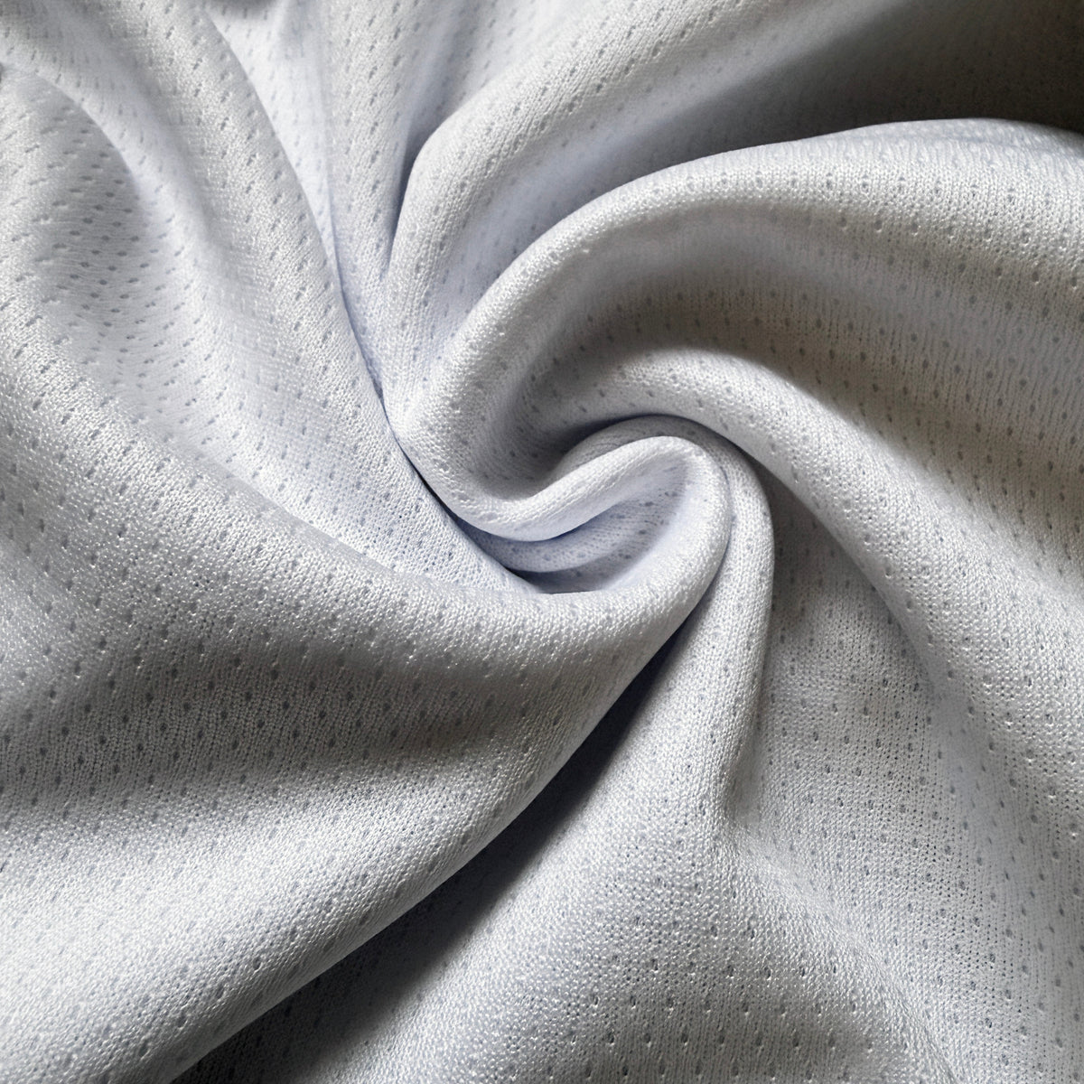 A close-up of light gray athletic mesh fabric, swirled in a spiral pattern to show its texture and weave.