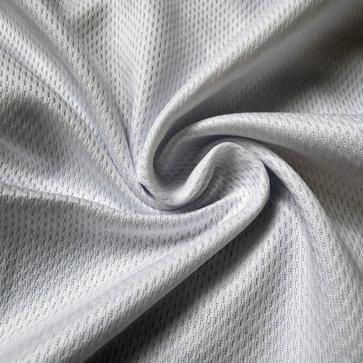 A close-up of light gray athletic mesh fabric, swirled in the center to show its texture and drape.