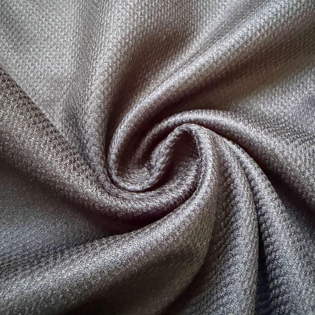A close-up of draped gray fabric with a textured, ribbed surface arranged in a spiral pattern.