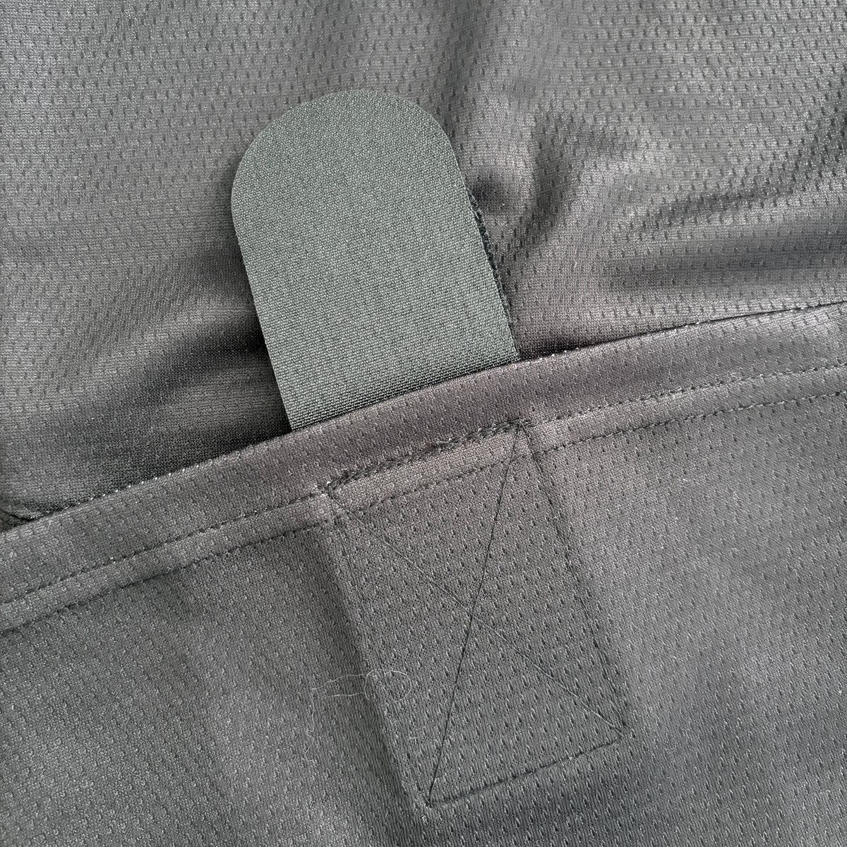 Close-up of a gray textured fabric product with a hook-and-loop fastener tab.