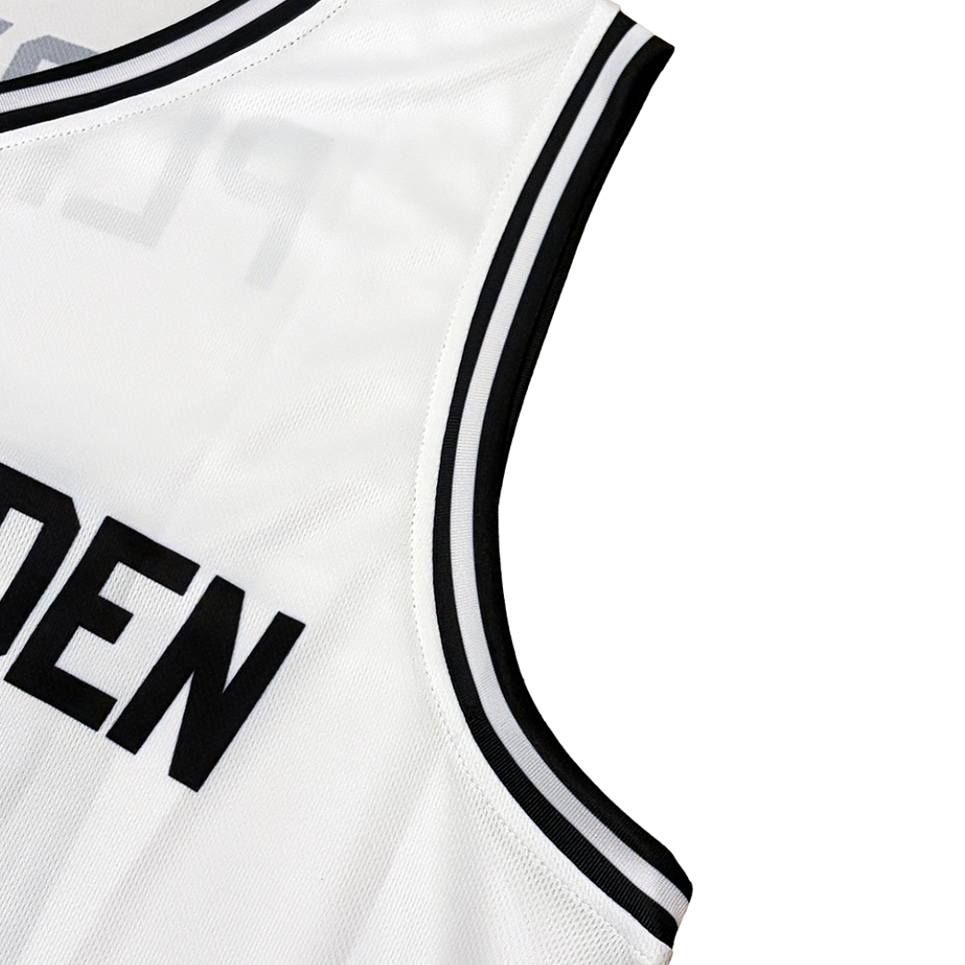 Close-up of a white basketball jersey sleeveless top with black and white striped trim and bold black lettering on the front, shown on a white background.