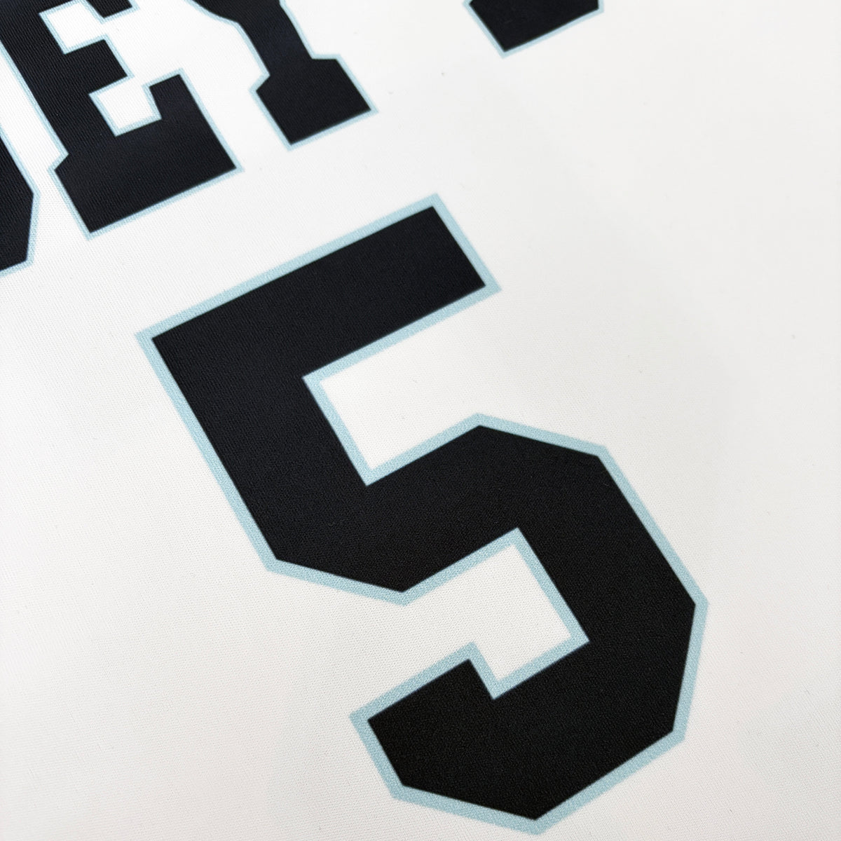 Close-up of a black athletic number 5 with a light blue outline on a white fabric background.
