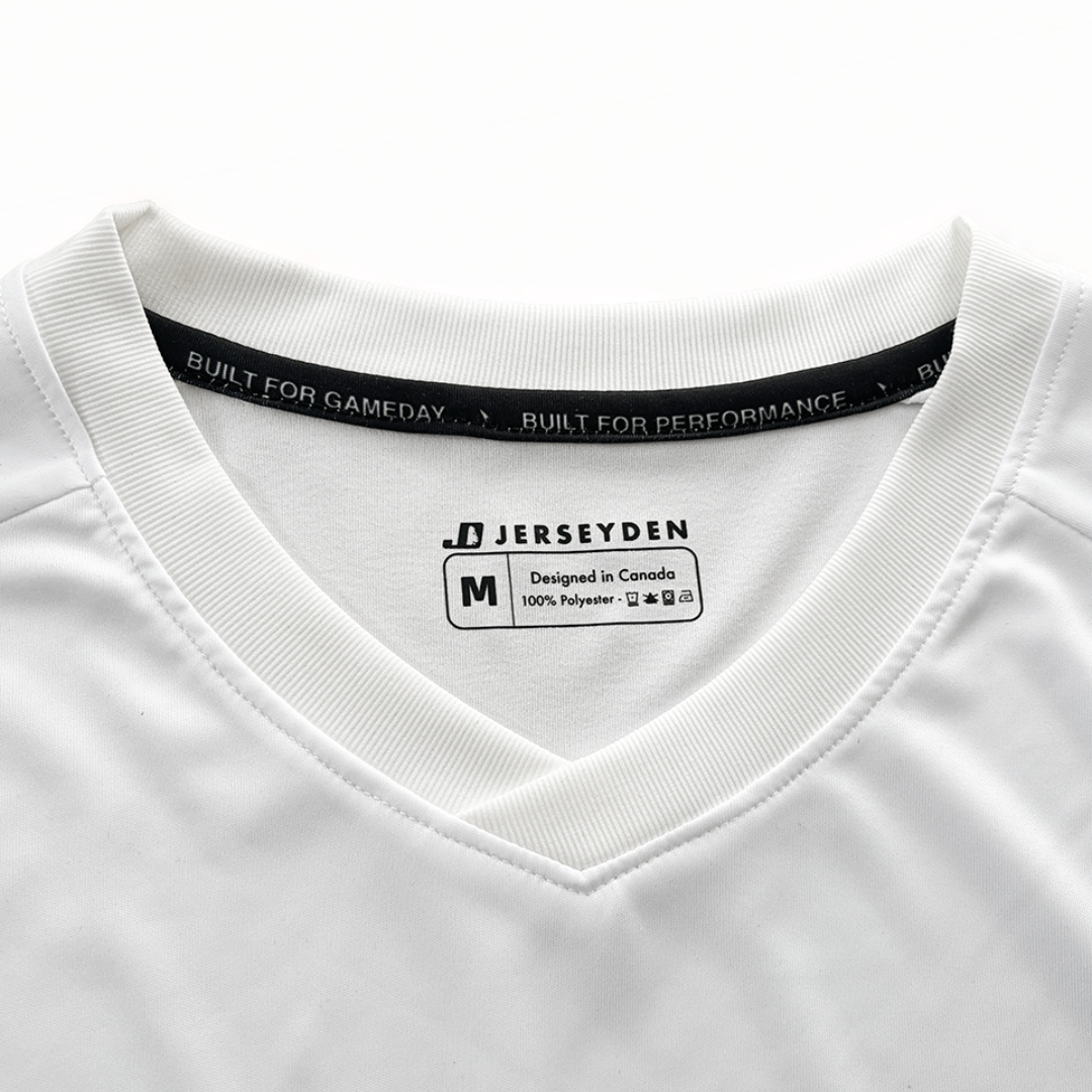 Close-up of a white v-neck athletic jersey with a black inner neck label reading 'BUILT FOR GAMEDAY' and a central sewn-in tag showing 'JERSEYDEN' and size M.